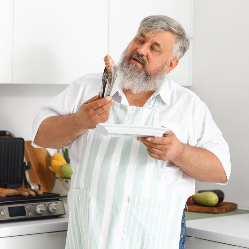 Man in a kitchen holding a spatula and a plate, with a neutral background